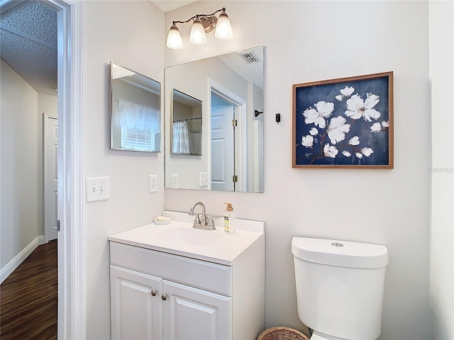 bathroom with hardwood / wood-style flooring, vanity, and toilet