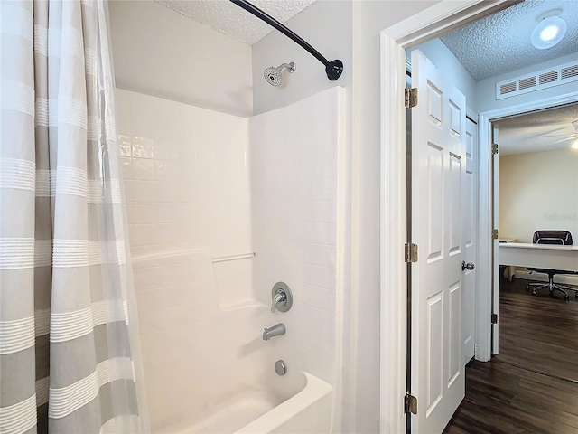 bathroom with hardwood / wood-style flooring, shower / bath combo, and a textured ceiling