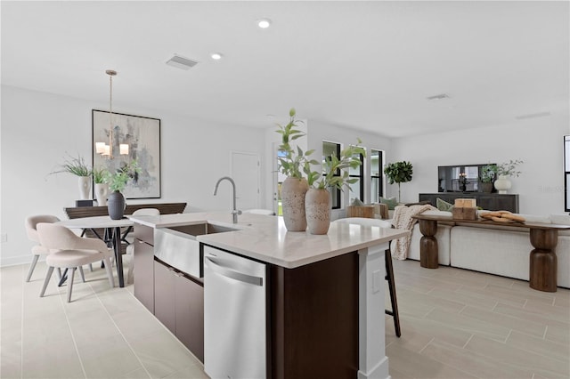 kitchen featuring sink, an inviting chandelier, dishwasher, hanging light fixtures, and an island with sink