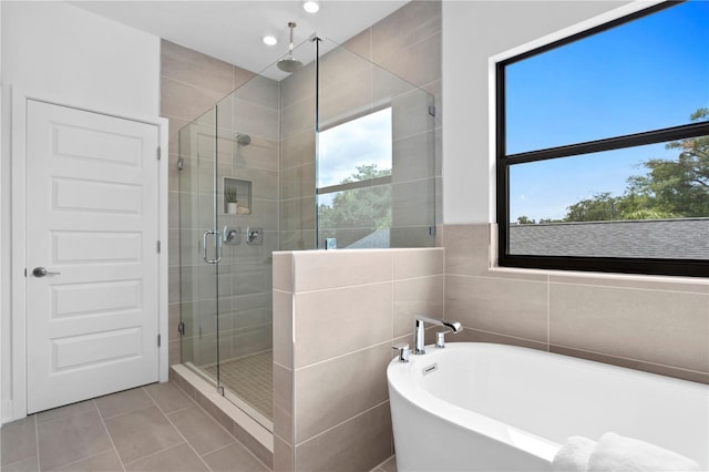 bathroom with tile patterned flooring, shower with separate bathtub, and tile walls