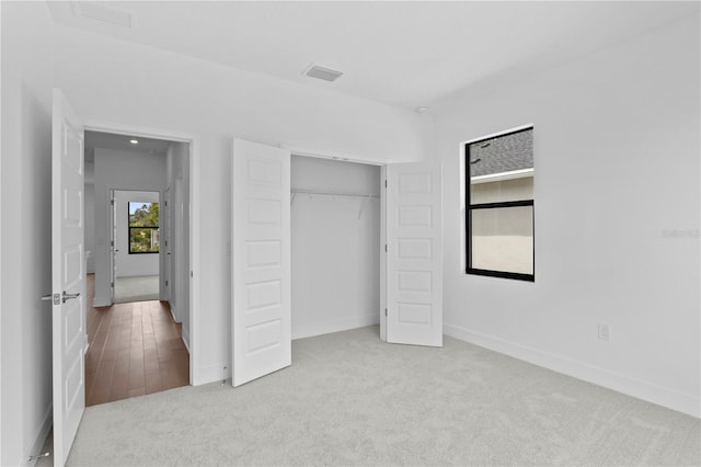 unfurnished bedroom with light colored carpet and a closet