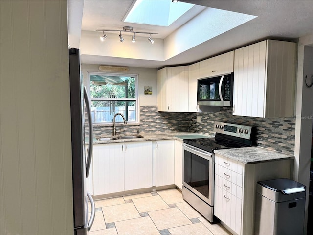 kitchen with sink, stainless steel appliances, tasteful backsplash, light stone counters, and white cabinets