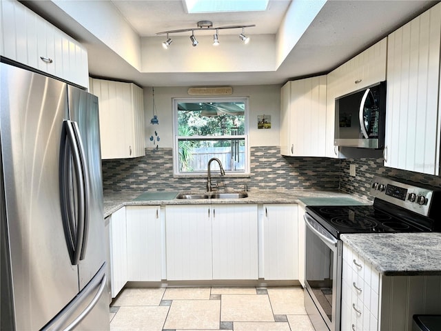 kitchen featuring stainless steel appliances, a raised ceiling, sink, and light stone countertops