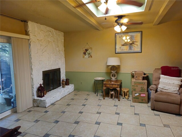 living room featuring beam ceiling, a fireplace, and ceiling fan