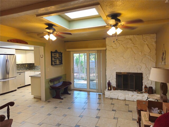 living room featuring ceiling fan, a fireplace, and a textured ceiling