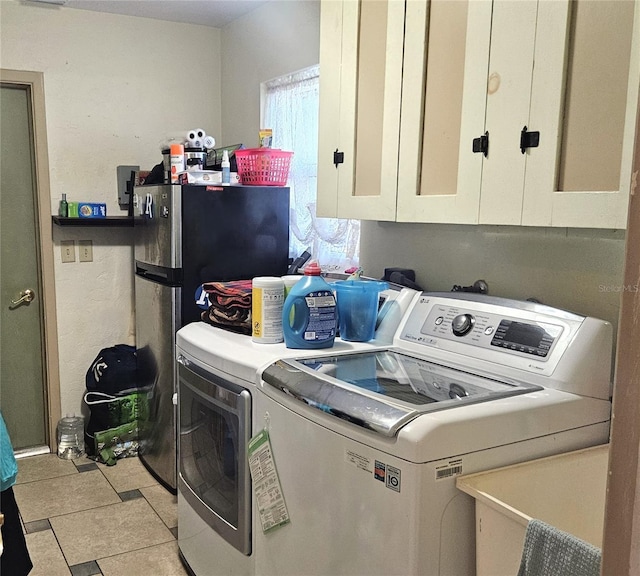 clothes washing area with light tile patterned floors, cabinets, and washing machine and clothes dryer