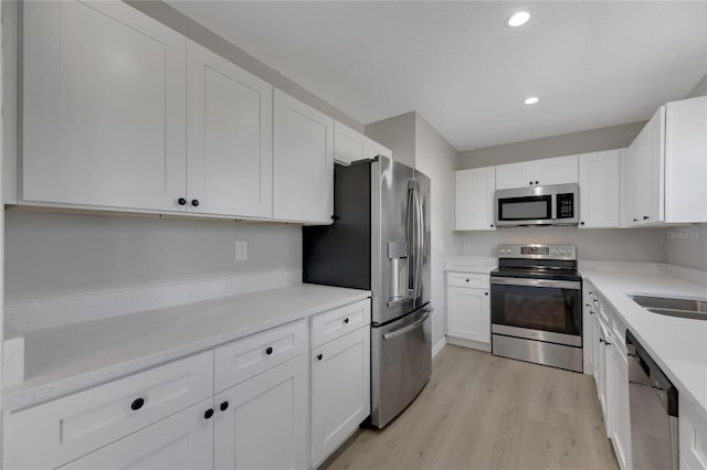 kitchen with light hardwood / wood-style floors, white cabinetry, and stainless steel appliances