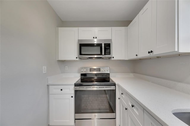 kitchen with white cabinetry, light stone counters, and appliances with stainless steel finishes