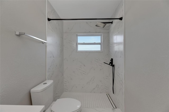 bathroom featuring toilet and a tile shower