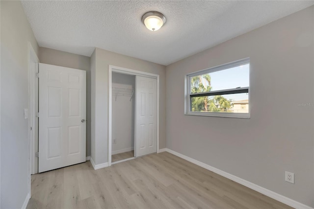 unfurnished bedroom with a closet, a textured ceiling, and light wood-type flooring