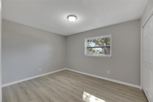 empty room with a textured ceiling and light hardwood / wood-style flooring