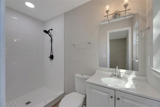 bathroom featuring vanity, toilet, and tiled shower