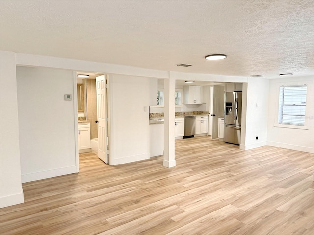 unfurnished living room with light wood-type flooring and a textured ceiling