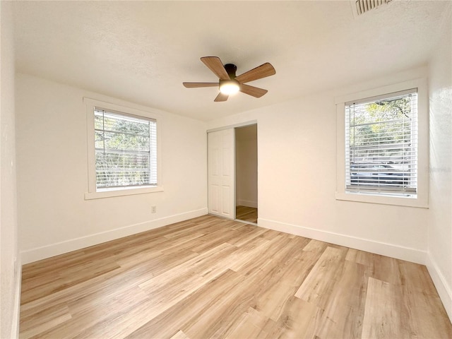 unfurnished bedroom with ceiling fan, a closet, a textured ceiling, and light hardwood / wood-style flooring