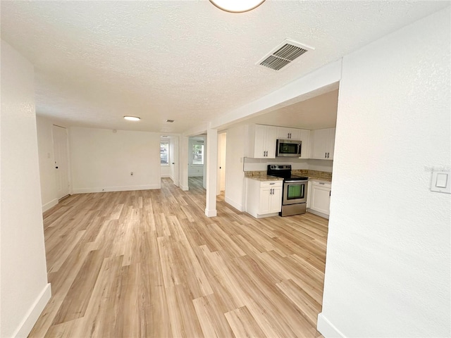 unfurnished living room with a textured ceiling and light hardwood / wood-style floors