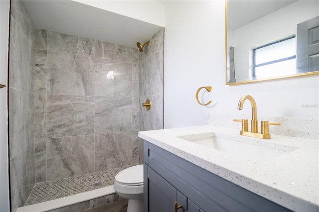 bathroom with toilet, vanity, and a tile shower