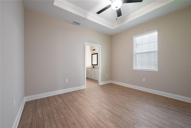 spare room featuring a raised ceiling, ceiling fan, light wood-type flooring, and ornamental molding