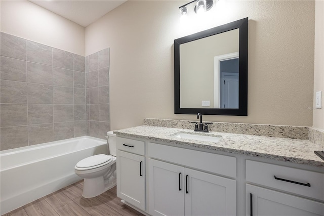 full bathroom featuring tiled shower / bath, hardwood / wood-style floors, vanity, and toilet