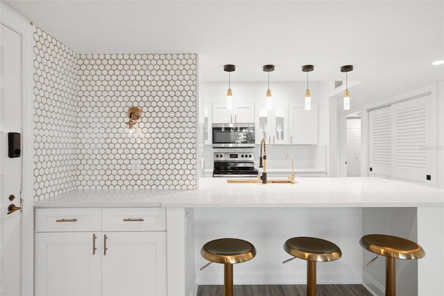 kitchen featuring a kitchen breakfast bar, dark wood-type flooring, white cabinets, and stainless steel appliances