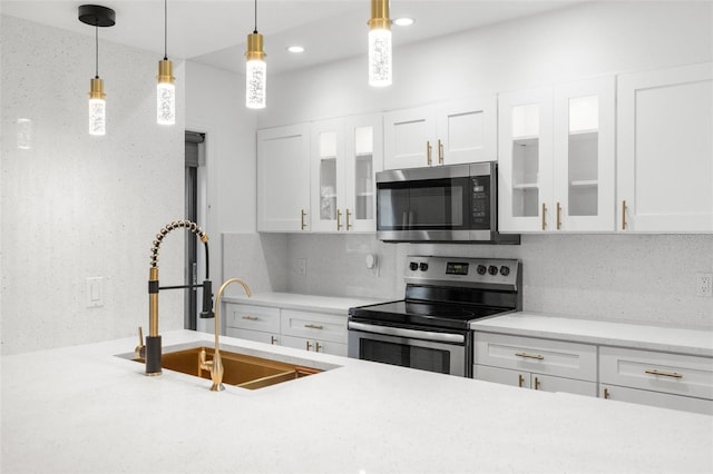 kitchen featuring decorative backsplash, stainless steel appliances, sink, white cabinets, and hanging light fixtures