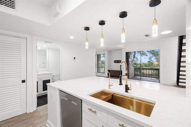 kitchen featuring sink, dishwasher, light hardwood / wood-style floors, white cabinetry, and hanging light fixtures