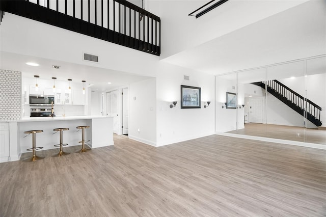 unfurnished living room with a towering ceiling and light hardwood / wood-style floors