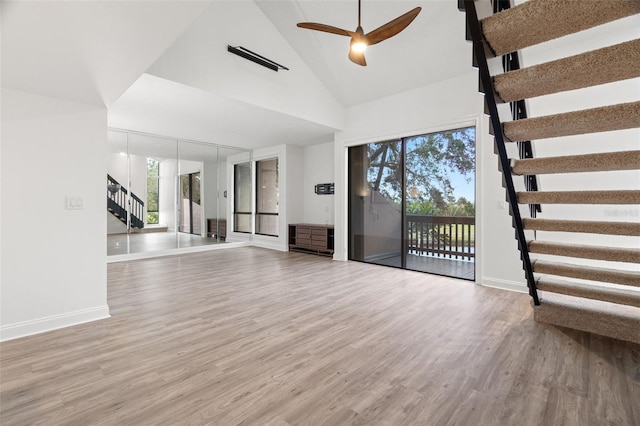 unfurnished living room with ceiling fan, light wood-type flooring, and high vaulted ceiling