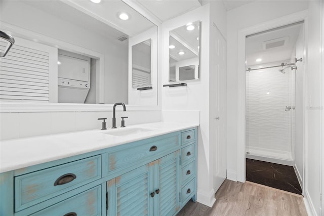 bathroom featuring vanity, wood-type flooring, walk in shower, and stacked washer and clothes dryer