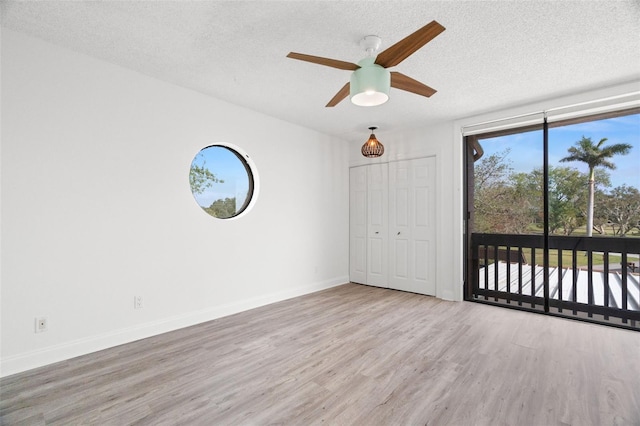 empty room with ceiling fan, a textured ceiling, and light wood-type flooring