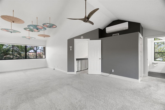 unfurnished room featuring vaulted ceiling, carpet flooring, a healthy amount of sunlight, and a wall mounted air conditioner