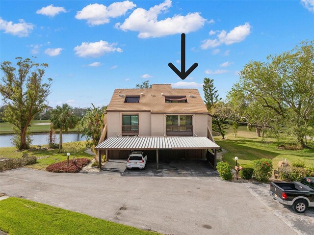 view of front of property featuring solar panels, a water view, and a front lawn