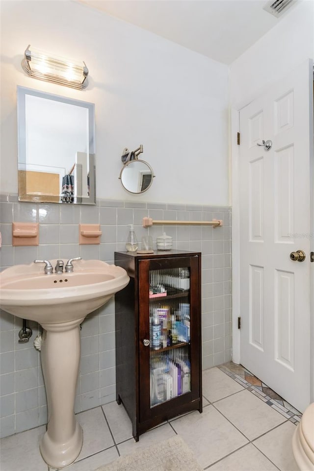 bathroom featuring tile patterned floors, tile walls, and toilet