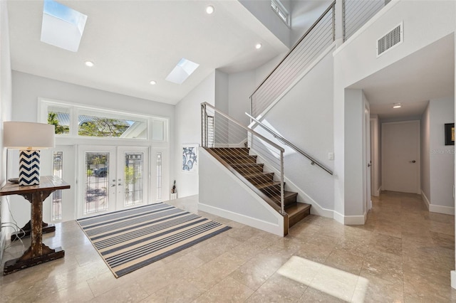 foyer entrance with french doors, high vaulted ceiling, and a skylight