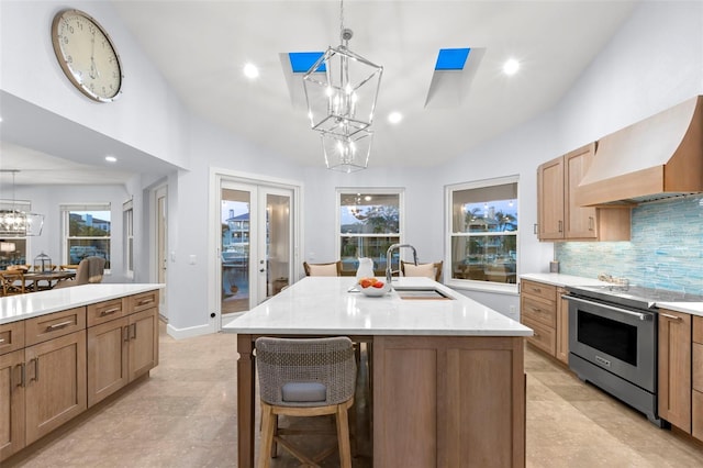 kitchen with stainless steel electric range oven, pendant lighting, lofted ceiling, custom exhaust hood, and a center island with sink