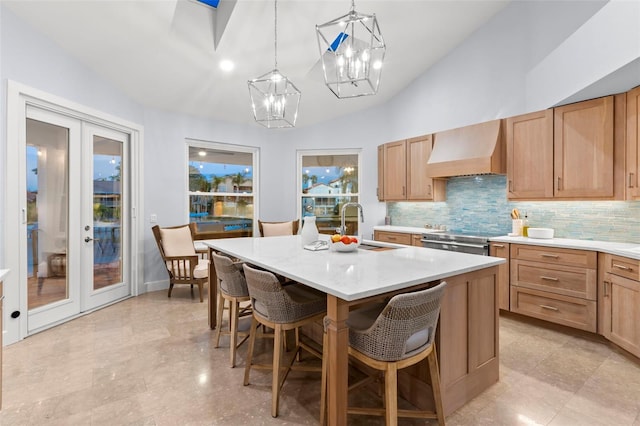 kitchen featuring vaulted ceiling, a kitchen island, decorative light fixtures, sink, and custom exhaust hood