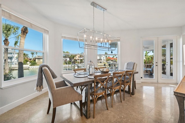 dining room with a water view, french doors, and a notable chandelier