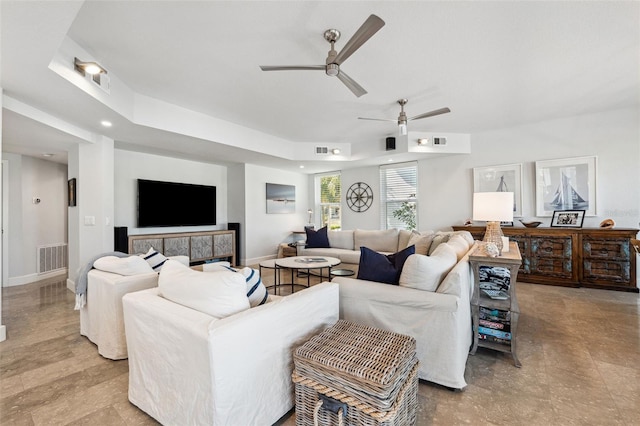 living room featuring a raised ceiling and ceiling fan