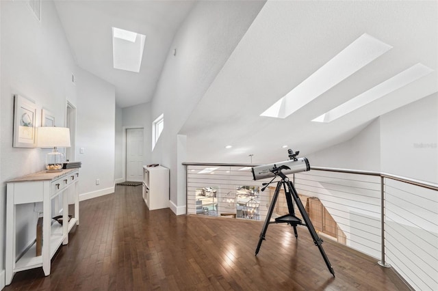 interior space featuring dark hardwood / wood-style flooring, high vaulted ceiling, and a skylight