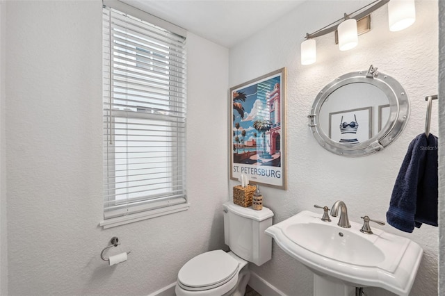 bathroom featuring a healthy amount of sunlight, sink, and toilet