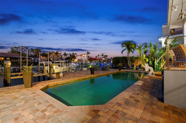 pool at dusk with a dock and a patio