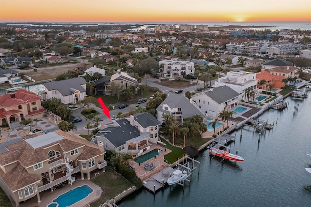 aerial view at dusk featuring a water view