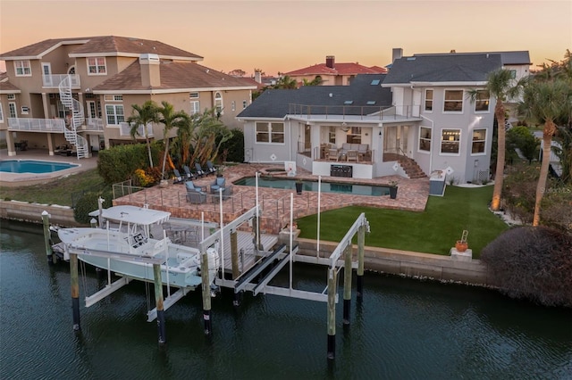 view of dock featuring a lawn, a patio, a balcony, and a water view