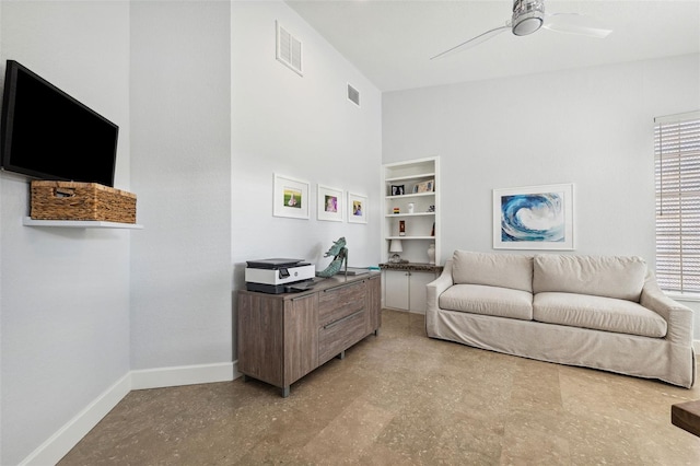 living room with built in shelves and ceiling fan