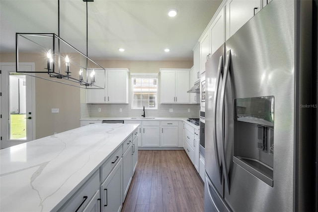 kitchen featuring stainless steel fridge, light stone counters, decorative light fixtures, light hardwood / wood-style flooring, and white cabinets