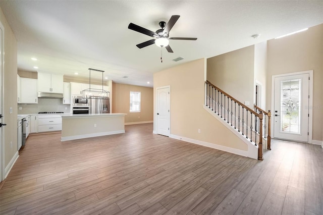 unfurnished living room featuring ceiling fan, plenty of natural light, and light hardwood / wood-style floors