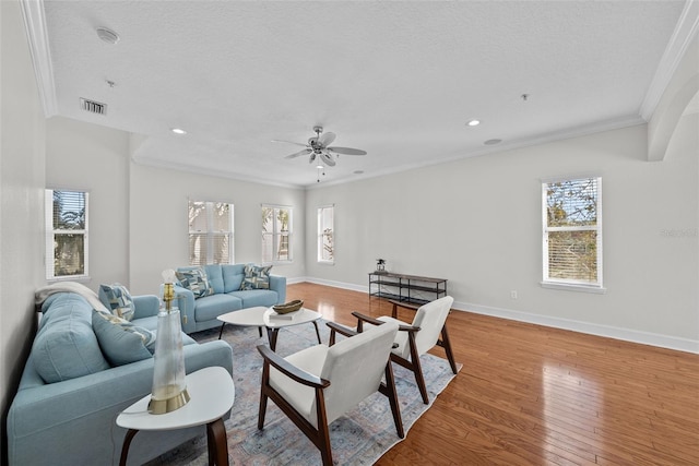 living room featuring crown molding, ceiling fan, a textured ceiling, and light hardwood / wood-style floors