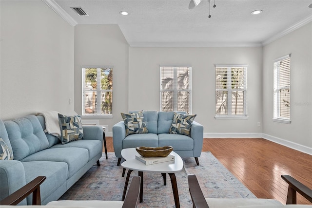 living room with a wealth of natural light, hardwood / wood-style floors, and crown molding