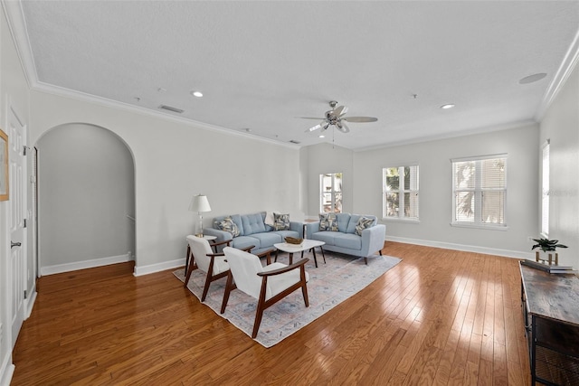 living room with wood-type flooring, ornamental molding, and ceiling fan