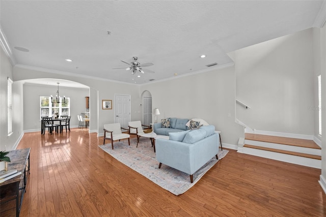 living room featuring ceiling fan with notable chandelier, wood-type flooring, and ornamental molding