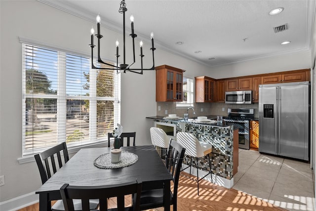 kitchen with light tile patterned floors, stainless steel appliances, decorative backsplash, kitchen peninsula, and a chandelier